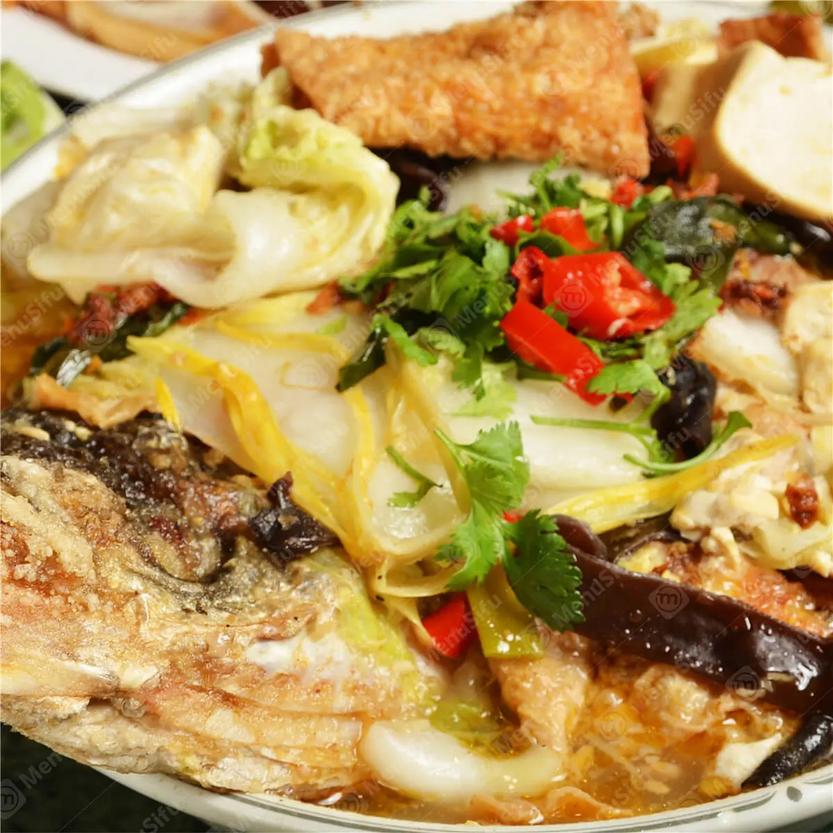 Whole fish in a clay pot with vegetables, tofu, and cilantro